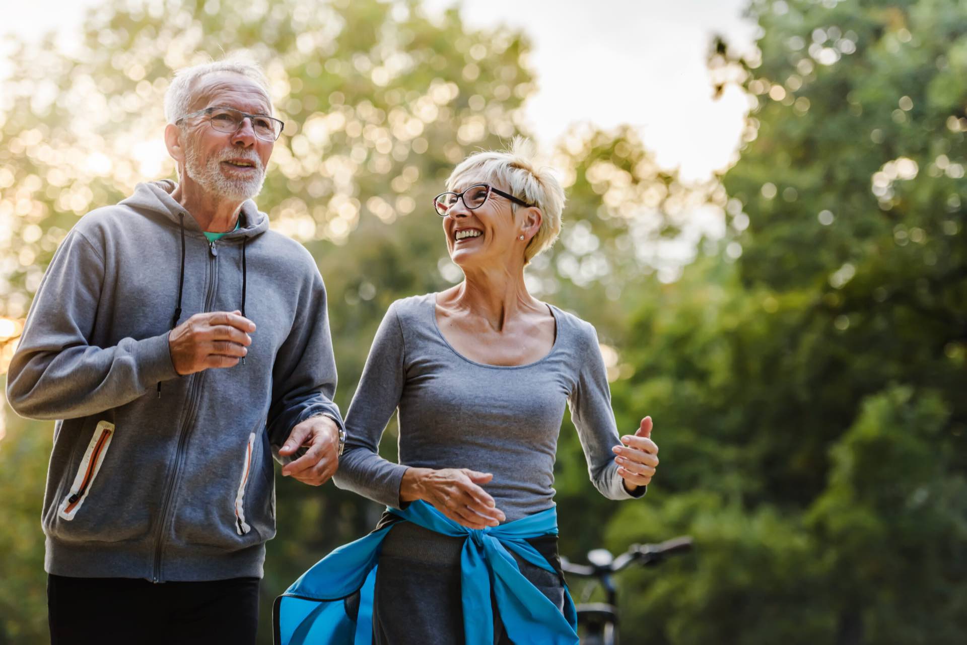 An older couple jogging together through a park