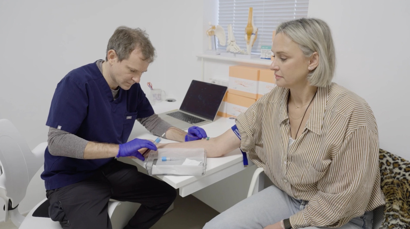 A clinician taking a small blood sample from a patient’s arm to prepare PRP